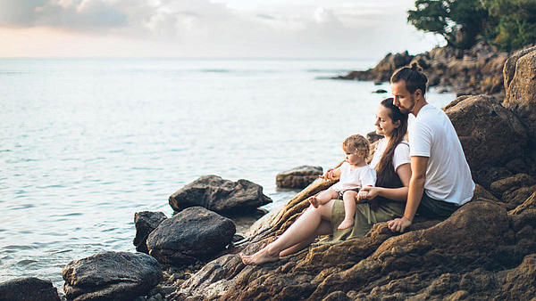 A family sits by the sea