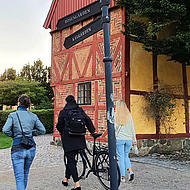 Three people walking in front of a half-timbered house in Ystad