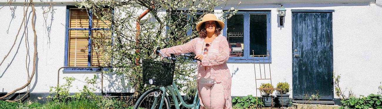 A woman stands with her bicycle in front of an old building in Ystad