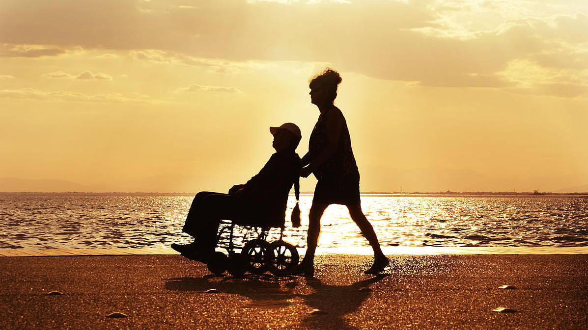 Eine Frau schiebt einen Rollstuhl am Strand