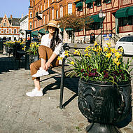 Frau mit Hut auf Bank in Ystad.