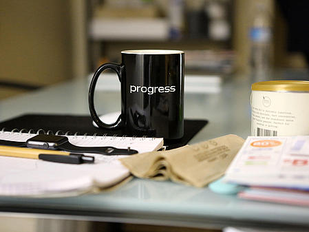 Cup with imprint "progress" on a desk.