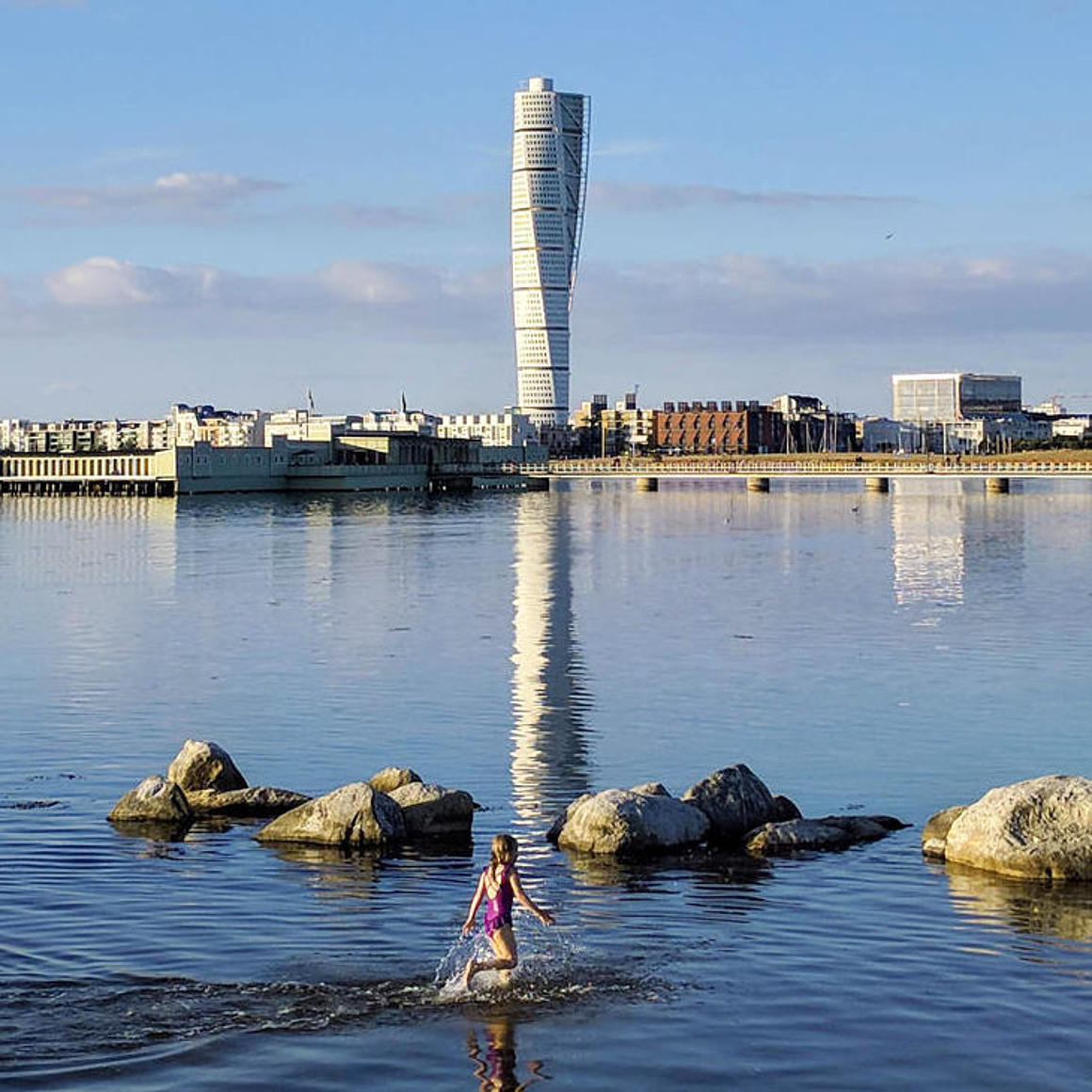 The Turning Torso Malmö is reflected in the water.