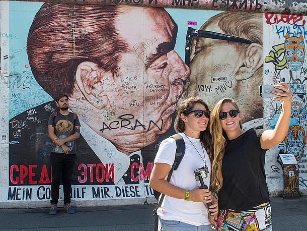Zwei Mädchen machen ein Selfie vor der East Side Gallery in Berlin. 
