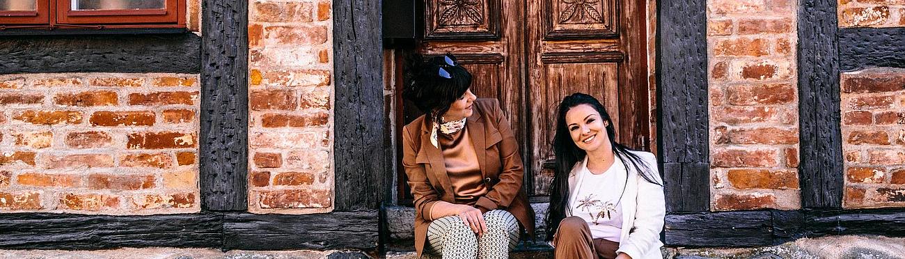 Two women sitting in front of a wooden door in Ystad